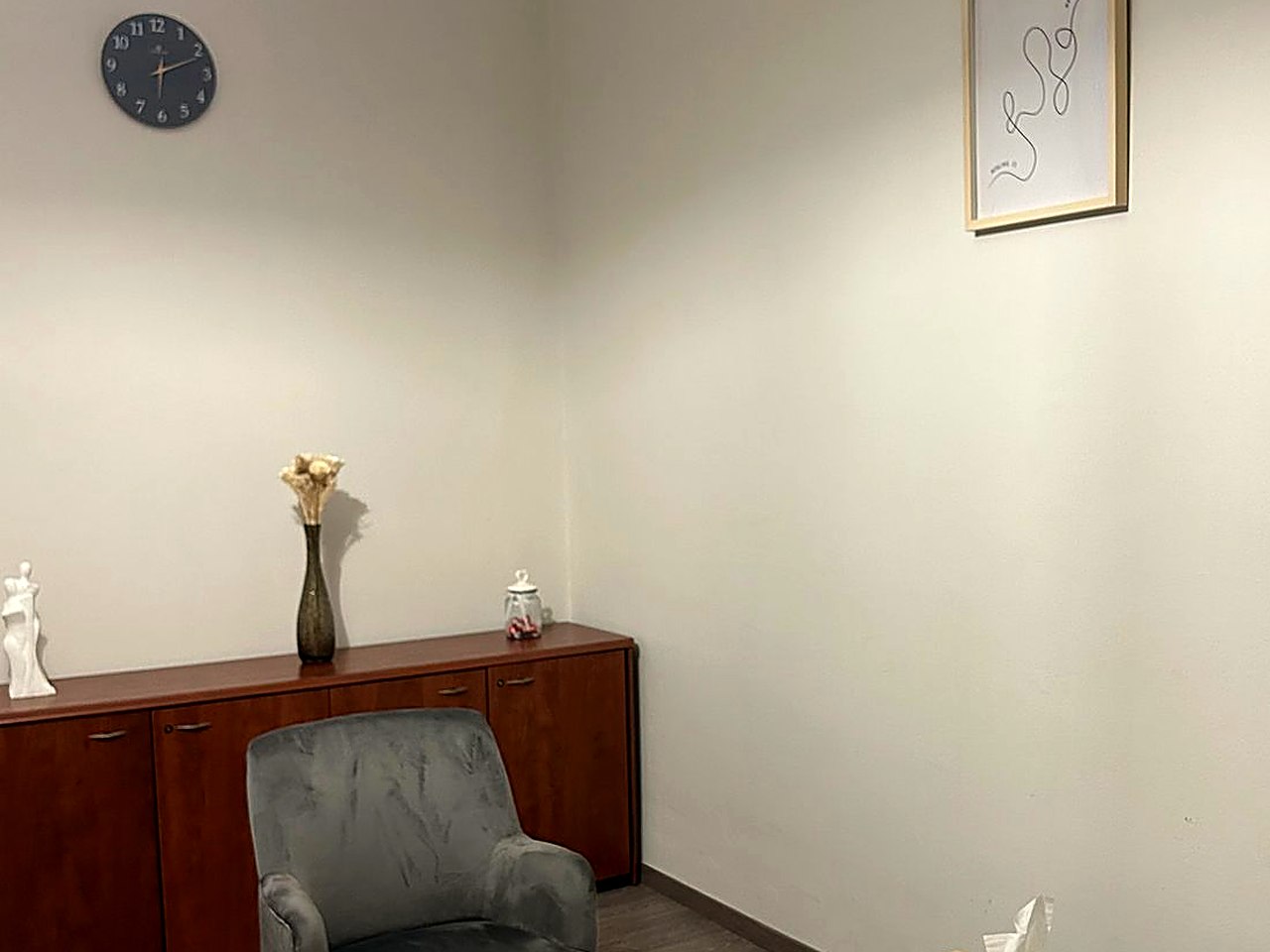 Un angolo dello studio: un orologio, una credenza, una scritta alla parete